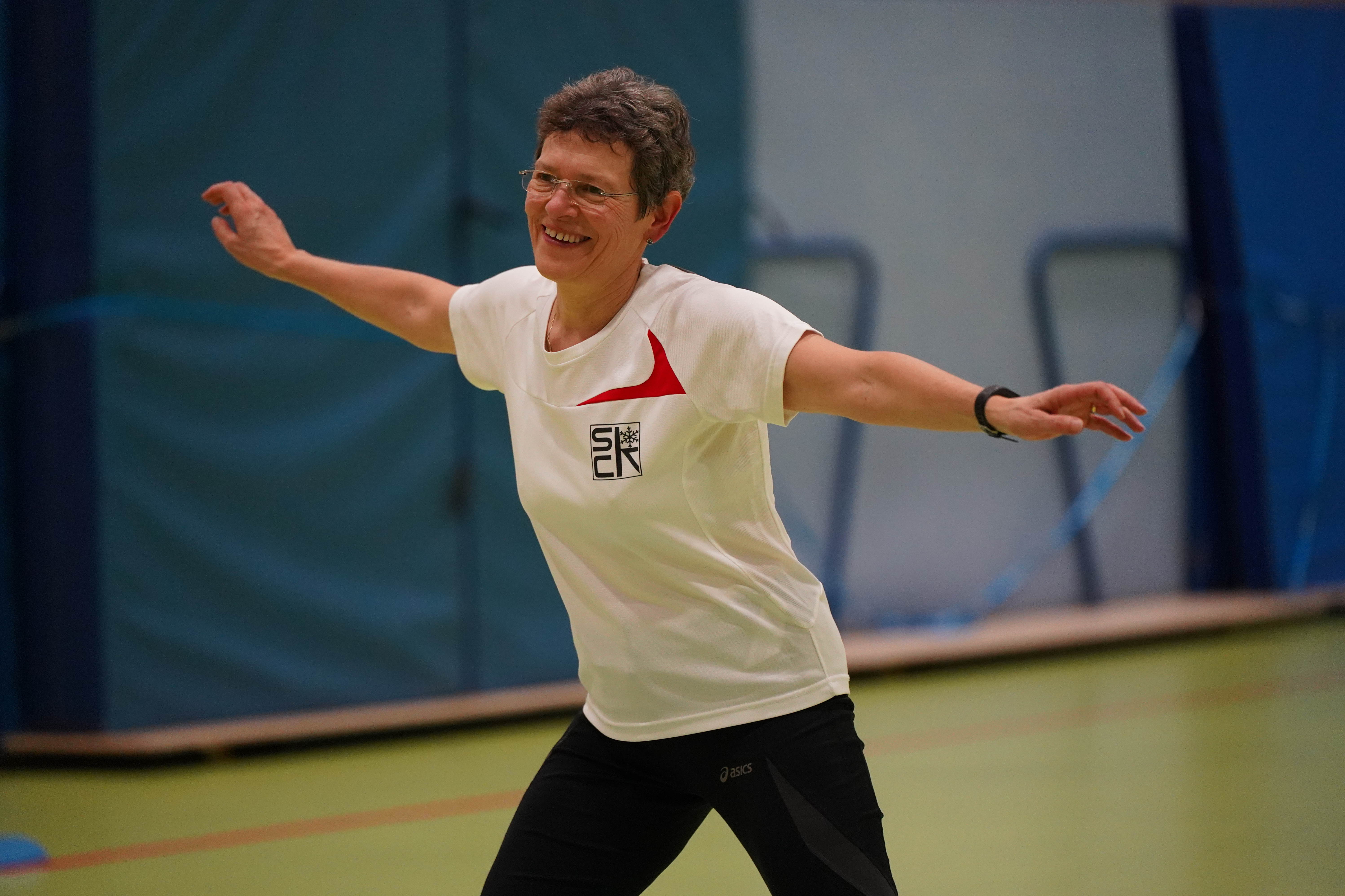 Eine ältere Frau macht eine Bewegung und lacht.