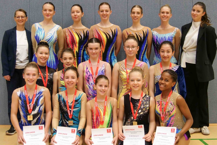 In drei Reihen präsentieren sich die Gymnastinnen mit ihren Medaillen