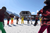 Eine Gruppe von Skifahrer*innen dehnen sich zusammen auf der Piste.