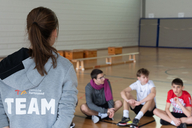Eine junge Frau erklärt Schülern etwas in der Sporthalle.