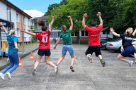 Personen sind in einer Reihe und springen hoch. Sie sind von hinten zu sehen.