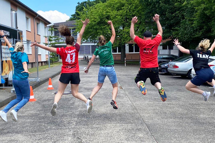 Personen sind in einer Reihe und springen hoch. Sie sind von hinten zu sehen.