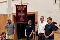 Vier Personen stehen vor einem Banner mit der Aufschrift "Turngau Kinzig", eine Person mit Mikro.