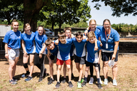 Junge Sportler und Sportlerinnen lachen Arm in Arm in die Kamera.