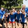 Junge Sportler und Sportlerinnen lachen Arm in Arm in die Kamera.