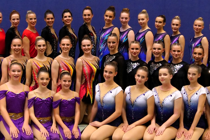Gymnastinnen in Kostümen posieren für ein Gruppenfoto.
