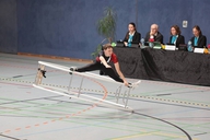 Ein Turner bei der Übung im Rhönrad, welches seitlich liegt