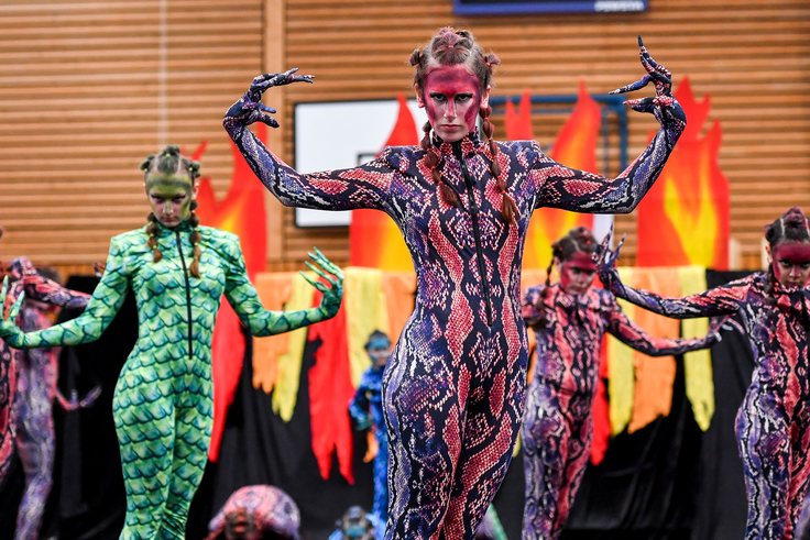 Junge Frauen in Drachen-Kostümen präsentieren eine Show.