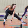 Frau in Sporthalle macht einen seitlichen Ausfallschritt.