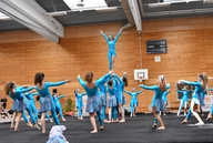 Eine Showgruppe in blauen Kostümen zeigt eine Choreographie mit Hebefigur.