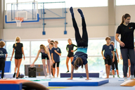 Kind durchläuft im Handstand einen Parkour aus Geräten in der Halle.