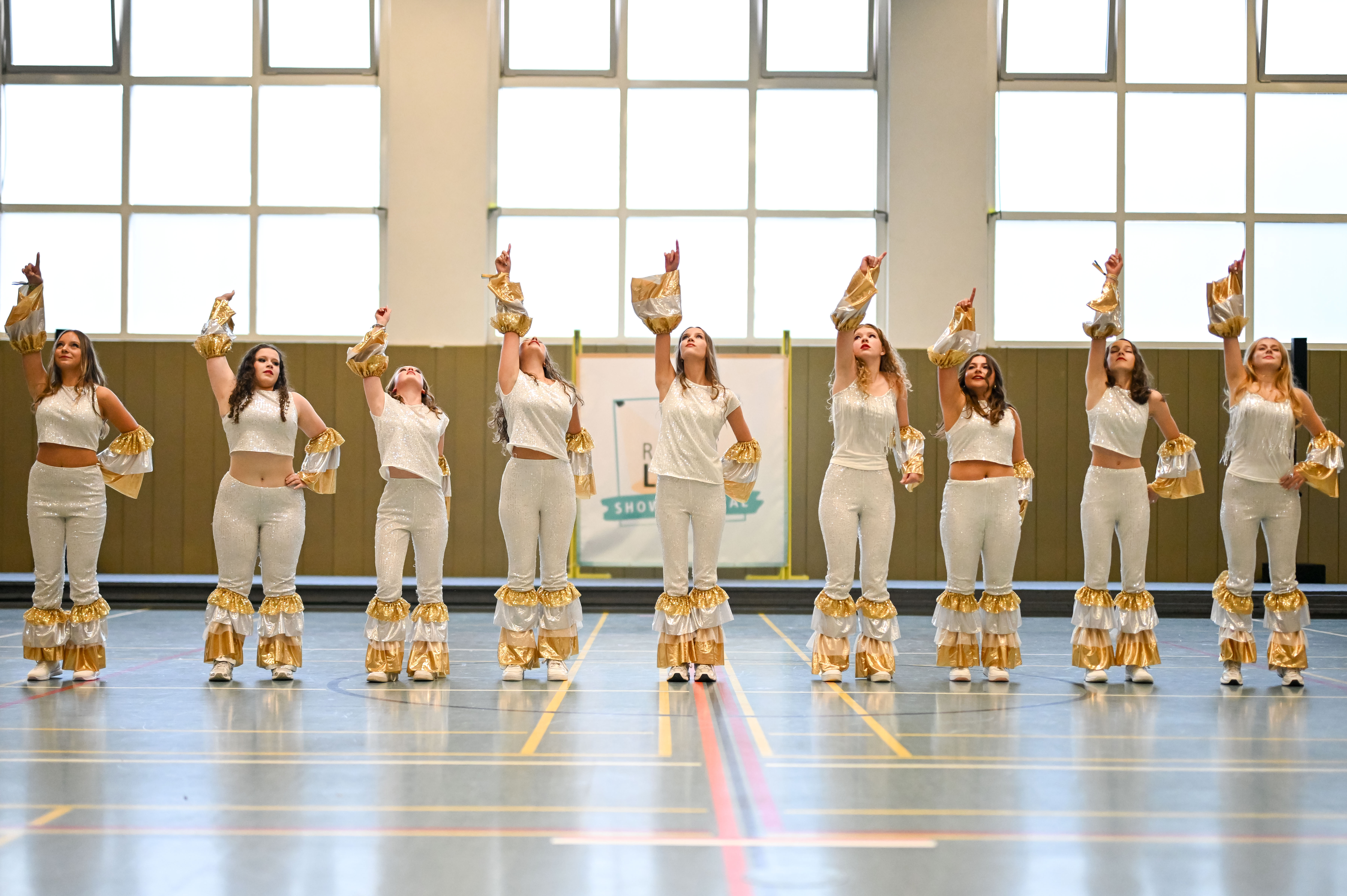 Ein Mädchengruppe tanzt in einer Sporthalle.
