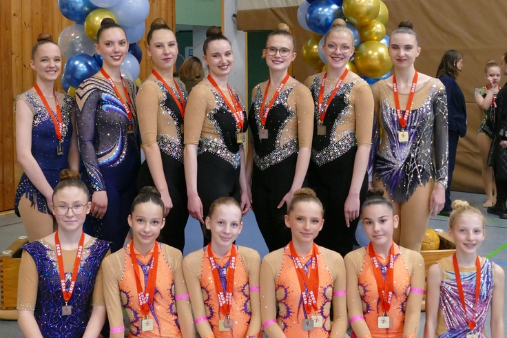 Mehrere Gymnastinnen posieren mit Medaillen.