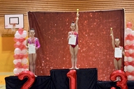 Drei Sportlerinnen stehen bei einer Siegerehrung auf einem Podest.