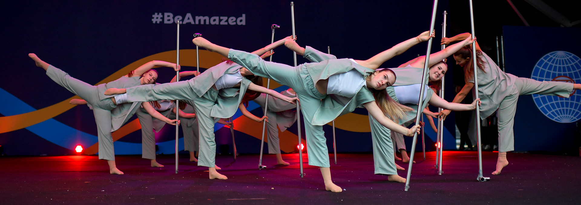 Tänzerinnen bewegen sich elegant an Stangen.
